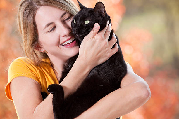 istock Woman Hugging Her Black Cat On Beautiful Fall Day 521027515