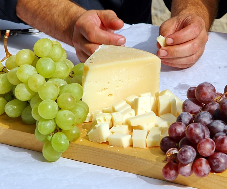 Wooden cutting board with Asiago cheese and black grapes and white grape
