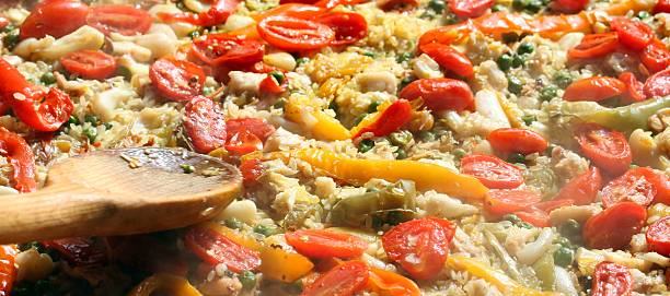 istock cooking Spanish paella with wooden spoon 521028653
