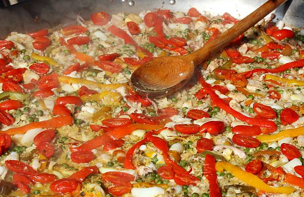 istock cooking Spanish paella with wooden spoon 521028659
