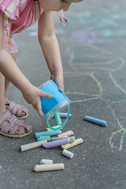 istock Little girl preparing for sidewalk chalk drawing on tarmac surface 521033736