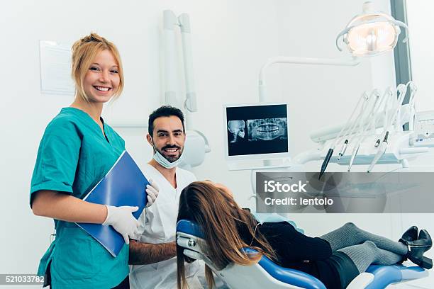 Dentist Doctor With The Assistant In The Clinic Stock Photo - Download Image Now - 30-39 Years, Adult, Apron