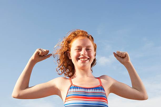 istock Girl flexing her muscles on the beach 521034920