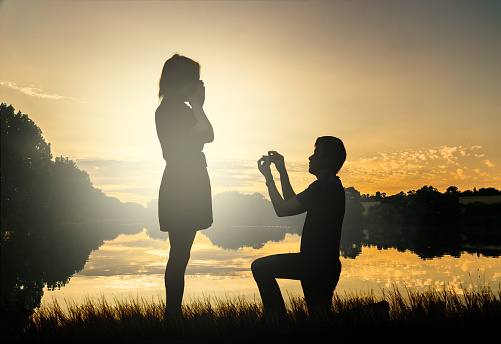 Boda propuesta. Novios en puesta de sol. Hombre dando anillo. photo