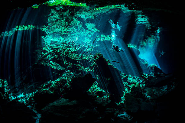 Amazing underwater places Scuba diver exploring the underwater cenotes in Mexico near Puerto Aventuras. Caves are dark and the light always gives different amazing ambient underwater. puerto aventuras stock pictures, royalty-free photos & images