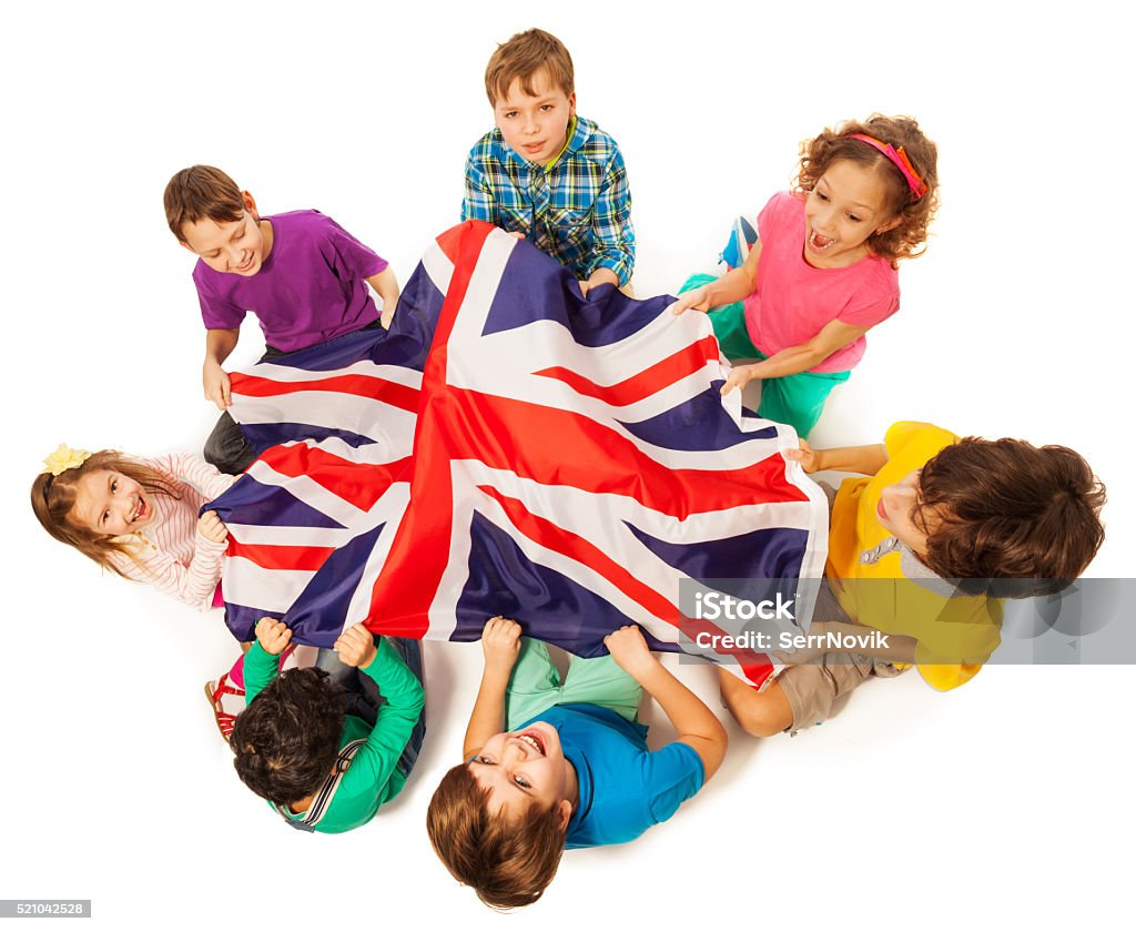 Kids with English flag in a middle of their circle Top view of seven kids holding English flag in the middle of their circle, isolated on white background England Stock Photo