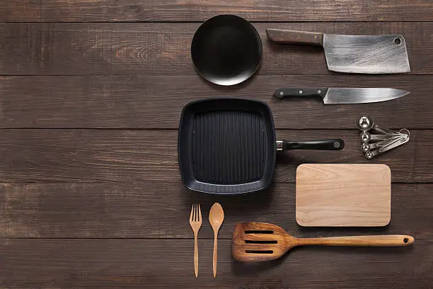 Various kitchenware utensils on the wooden background for cooking.