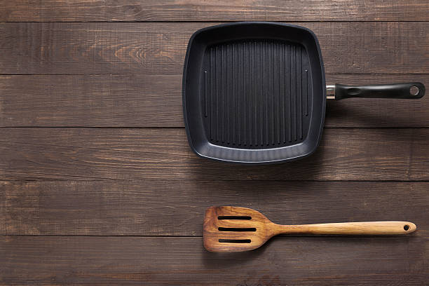 istock Cast iron griddle pan and turner wood on wooden background 521043150