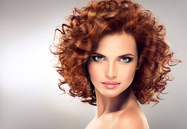 Pretty red haired girl with curls , fashionable makeup. Straight look on camera.