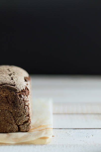Detail of homemade traditional bread, with golden crust, on a white wooden table.