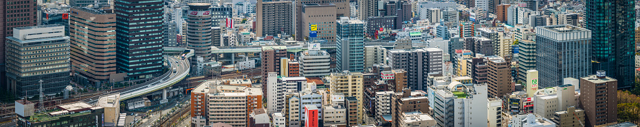 Aerial panoramic view across the crowded cityscape and futuristic skyline of central Osaka, from the skyscrapers of Umeda to the towers of Namba. ProPhoto RGB profile for maximum color fidelity and gamut.