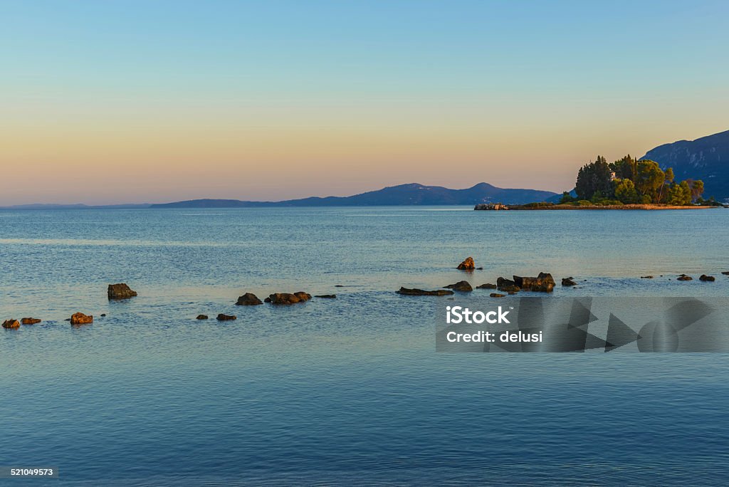 Sunset behind the Pontikonisi island at Corfu Greece A view on the sunset behind the Pontikonisi island at Corfu Island Greece with Corfu mountains in the background Abbey - Monastery Stock Photo