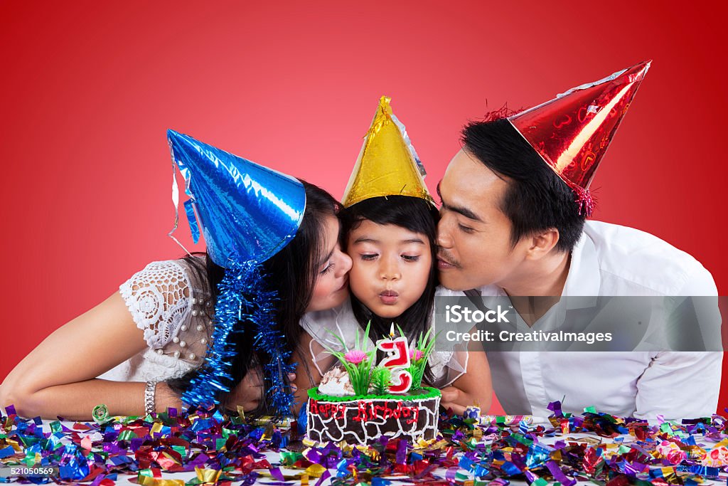 Family celebrate birthday with red background Asian family wearing party hats while celebrate little girl birthday Adult Stock Photo