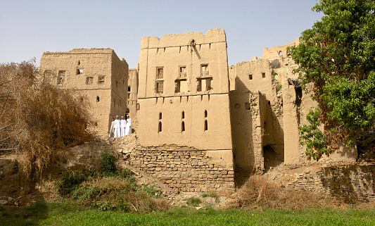 Birkat Al Mouz, Oman – February 2, 2008: Four young Omani men in traditional dress inspect the ruins of Birkat Al Mouz in the Nizwa area of the Sultanate of Oman.