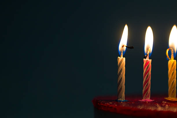 Beautiful Birthday cake with three candles lighting on top of white cream and red love symbol on the bakery cake for celebration, party or programs.
