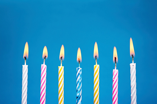 A row of burning birthday candles, on a blue background.. Canon 5D MK III