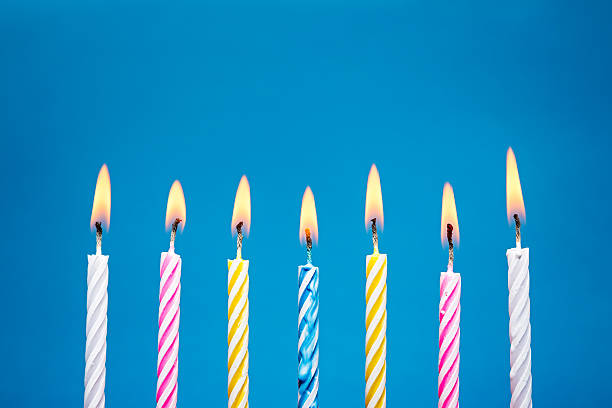 Flaming Birthday Candles on blue background A row of burning birthday candles, on a blue background.. Canon 5D MK III candlelight photos stock pictures, royalty-free photos & images