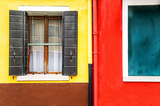istock Window with shutters open on a yellow and red wall. 521075690