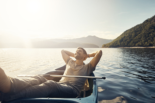 Shot of a young man relaxing in a boat out on a lake