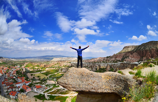 Cappadocia ,Turkey - July 13 ,2015 :  Young boy on a stone   with raised hands  in Goreme