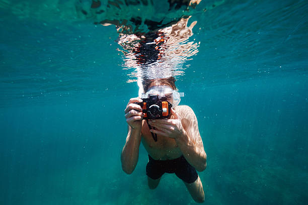 Breathtaking views... Shot of a young man taking pictures underwater underwater diving photos stock pictures, royalty-free photos & images