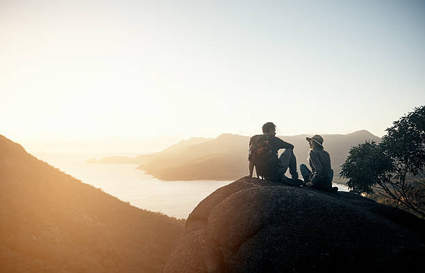 Climb was so worth it Shot of a young couple hiking the mountains in the morning silhouette lounge stock pictures, royalty-free photos & images