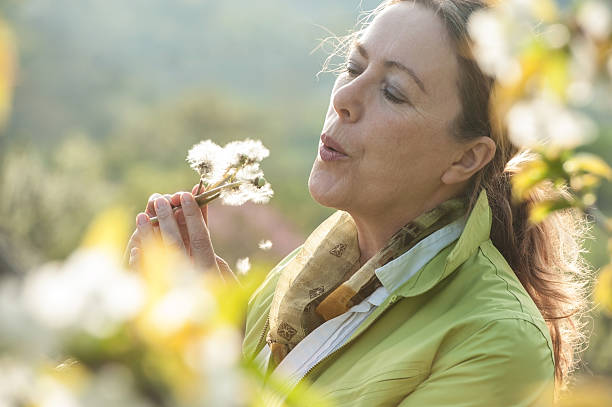 istock Mature woman blowing dandelion flower 521084590