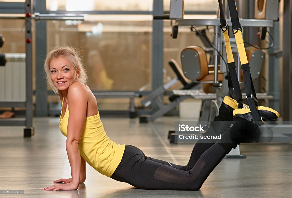 Fitness training exercises at gym woman Young woman doing push-ups while legs hanging on elastic rope Active Lifestyle Stock Photo