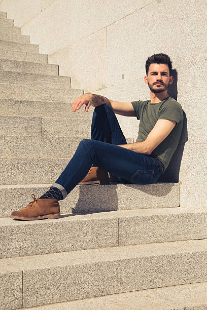 istock Trendy young man sitting on the stairs on sunny day 521085664