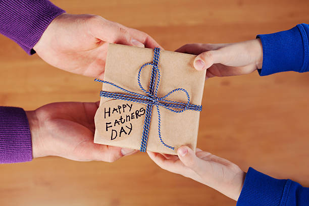 istock Childrens hands and daddy hands holding gift, Happy fathers day 521086886