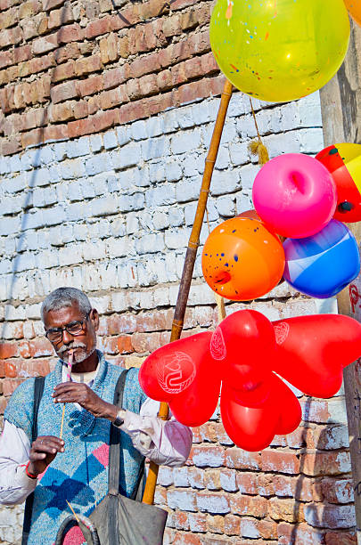 Barsana, India - March 10, 2014: An Indian man makes his living selling balloons and playing music on the streets of the old part of the city during holi festival.