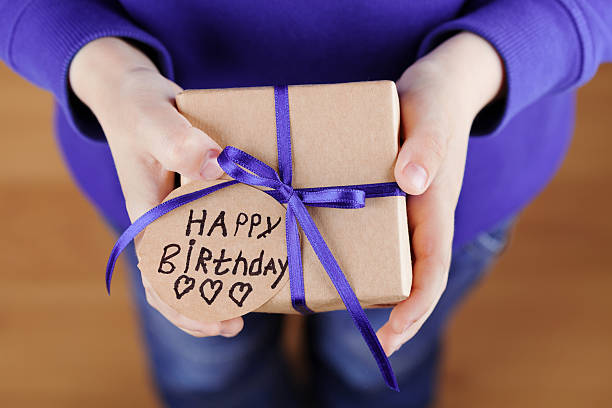 istock Childrens hands holding gift or present with tag Happy Birthday 521087338