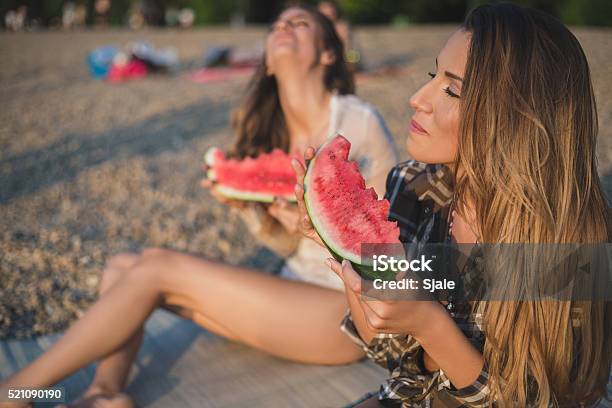 Girlfriends Laughing And Eating Watermelon On The Beach Stock Photo - Download Image Now