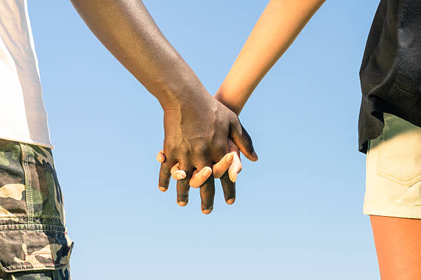 multirracial pareja en el amor a mano en mano contra el racismo - couple black american culture african culture fotografías e imágenes de stock