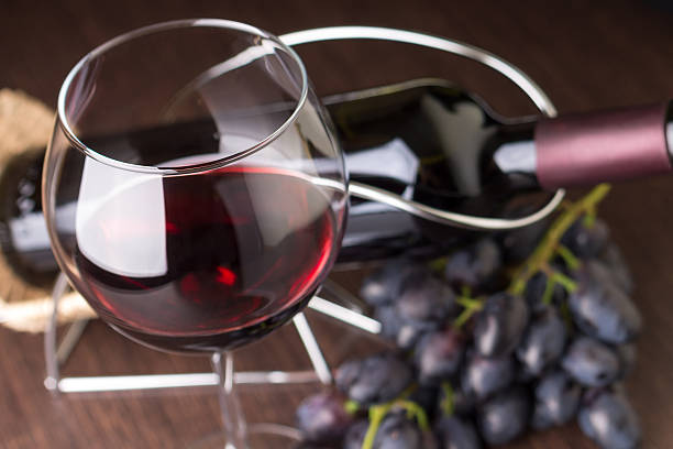 istock Wineglass with red wine with grapes and bottle at background 521108635