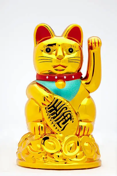 Close up shot of a golden Maneki-neko, a common Japanese figurine (lucky charm, talisman) which is often believed to bring good luck to its owner as well as beckoning customers and wealth. They are found throughout Asia.