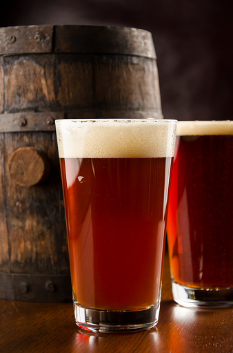 Pint glasses of Amber Ale (Beer) with a vintage Beer Barrel