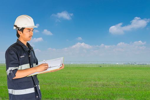 Engineer over Long fence and green grass on blue sky background.