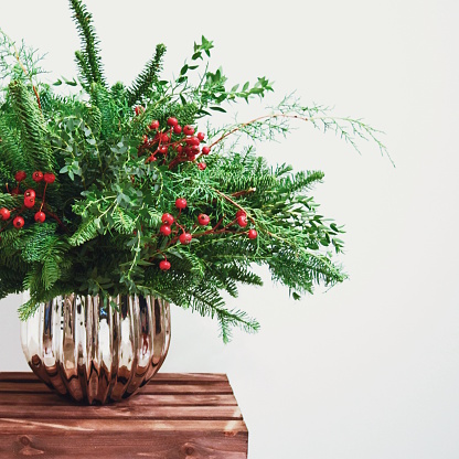 Festive greenery and berries planted in a silver vase. 