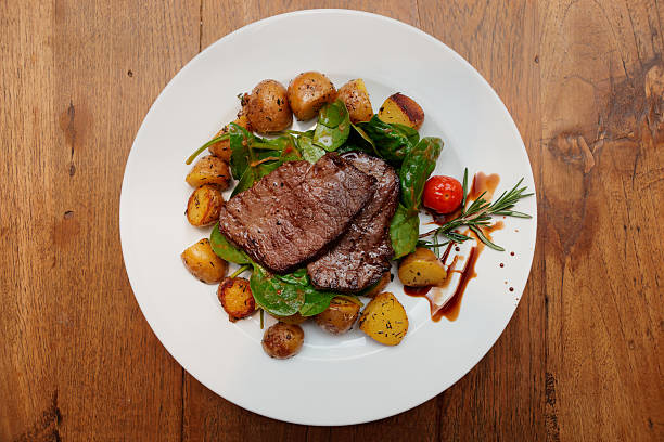 istock Steak with fried potatoes on wooden table 521135029