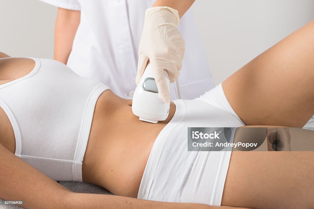 Woman Receiving Laser Treatment On Belly Close-up Of Woman Having Laser Treatment On Belly At Beauty Clinic Medical Laser Stock Photo