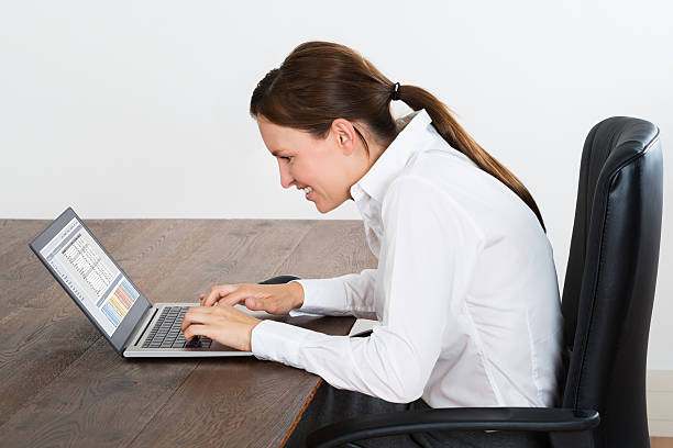 Happy Businesswoman Working On Laptop Young Happy Businesswoman Working On Laptop In Office bad posture stock pictures, royalty-free photos & images