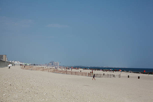 Keep off dunes sign at Rockaway Beach, Queens, New York City. Sunny Day with clouds and waves.