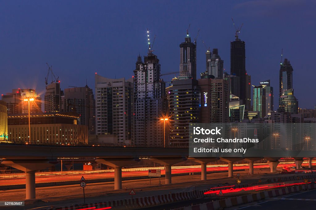 Dubai, UAE - Marina Towers during Blue Hour Dubai, United Arab Emirates - January 03, 2011: Construction continues unabated whether it is day or night on the towers of Dubai Marina. Photo shot after sunset from across Sheikh Zayed Road; the lights and tail lights of the traffic on the road can be seen as streaks of light due to the extended exposure time. In the foreground, the elevated tracks of Dubai Metro. Horizontal format; Copy space Apartment Stock Photo