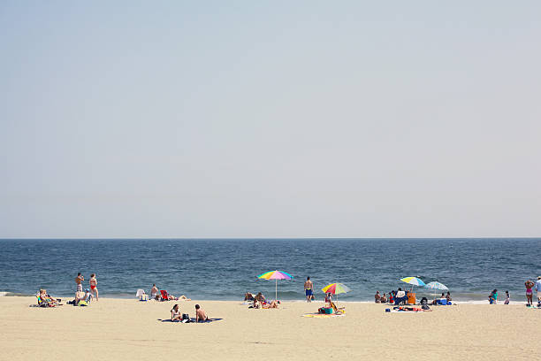 Diverse group of people enjoy day at the beach. People of all ages, sizes and color enjoy the beach. Rocking their swimsuits, bikinis and street wear.