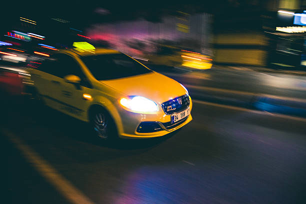Fast speed yellow taxi in the city traffic at night Istanbul, Turkey - October 25, 2014: Panning image of a yellow taxi at fast speed in Istanbul at night, Beyoglu district close to Galata Bridge on Tersane Cd. yellow taxi cab stock pictures, royalty-free photos & images