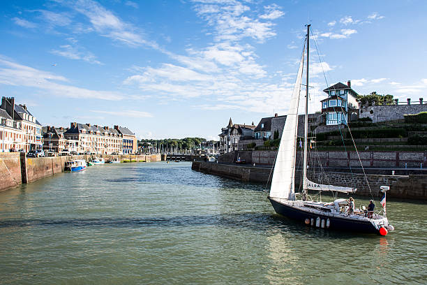 Saint Valery en Caux, France - July 6, 2014: a vessel returns to port at sunset. On the two sides of the picture, the typical houses.