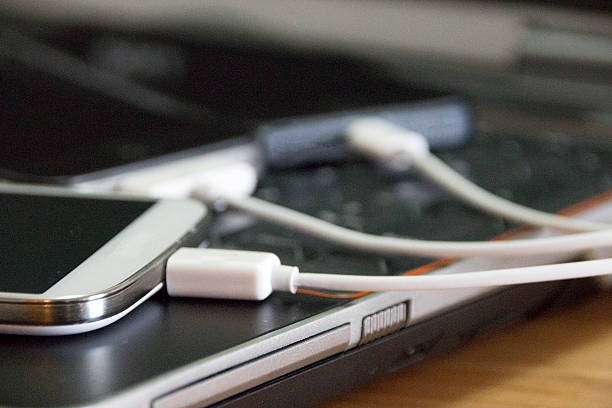 Mobile business devices Smartphones charged by a laptop computer. phone charger cable stock pictures, royalty-free photos & images