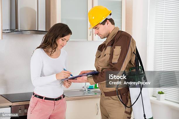 Woman Signing Document In Front Of Exterminator Stock Photo - Download Image Now - Exterminator, Pest Control Equipment, Customer