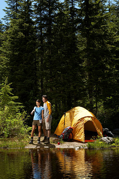 para stojąca na brzegu wody, przy namiocie - camping hiking tent couple zdjęcia i obrazy z banku zdjęć
